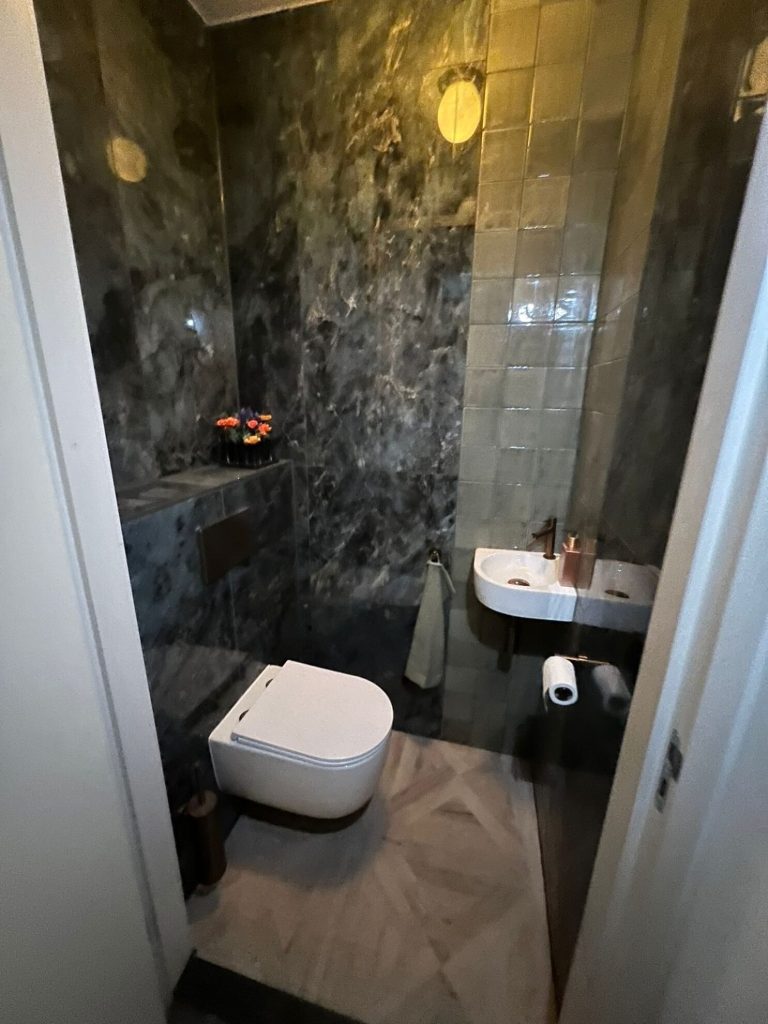 Modern toilet donkere marmerlook tegels hangtoilet fonteintje