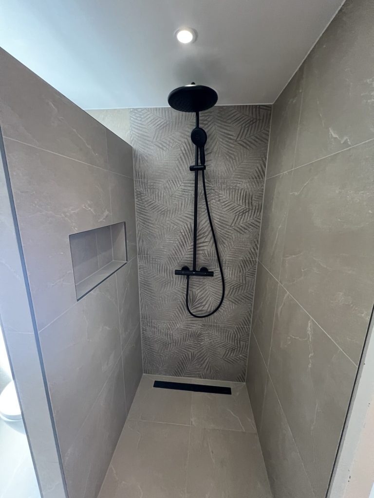 Moderne badkamer ligbad beige tegels zwarte kranen scaled